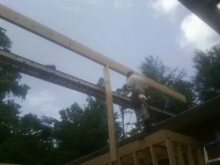 Carpenter setting a ridge beam over a new addition frame — Ice Dam Removal by Roofing Brothers in Wheatland