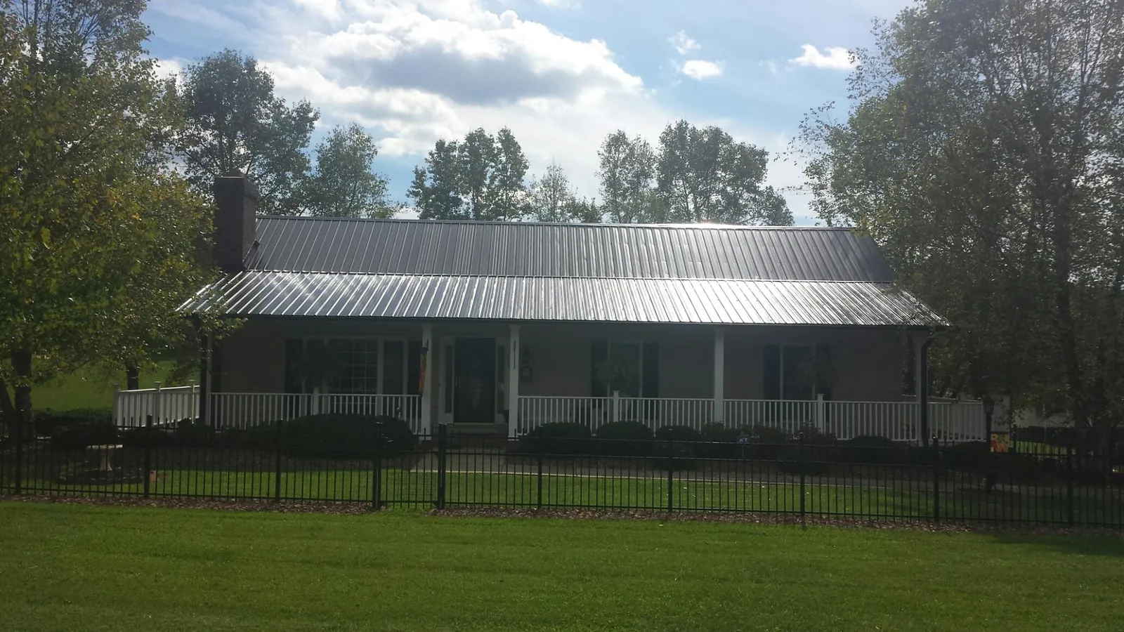 Gray metal roof on a brick ranch with a full width front porch — Gutter Guard Installation work by our crew in Wheatland
